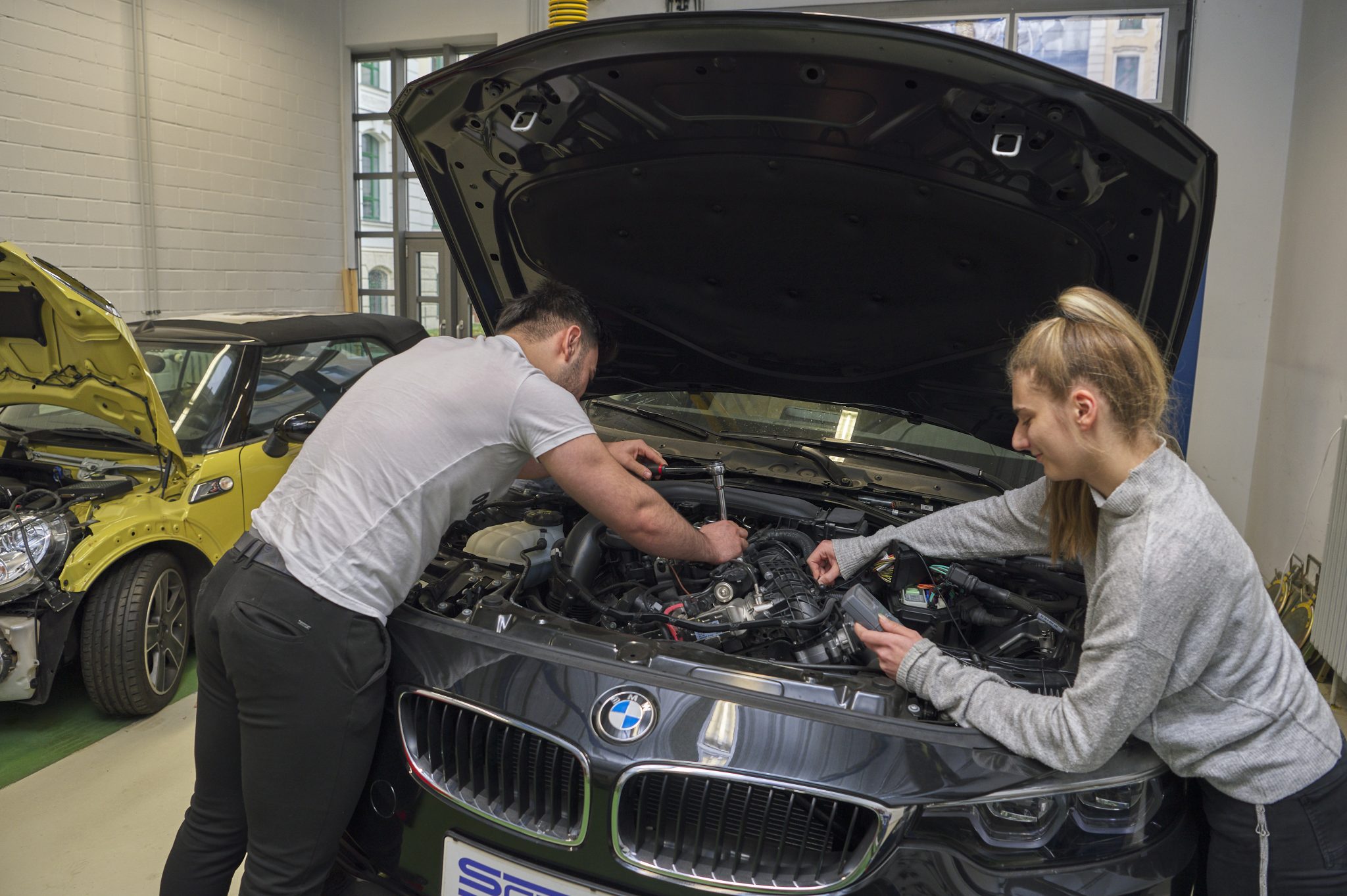 Auszubildende arbeiten gemeinsam an einem Fahrzeug in der schulischen Werkstatt